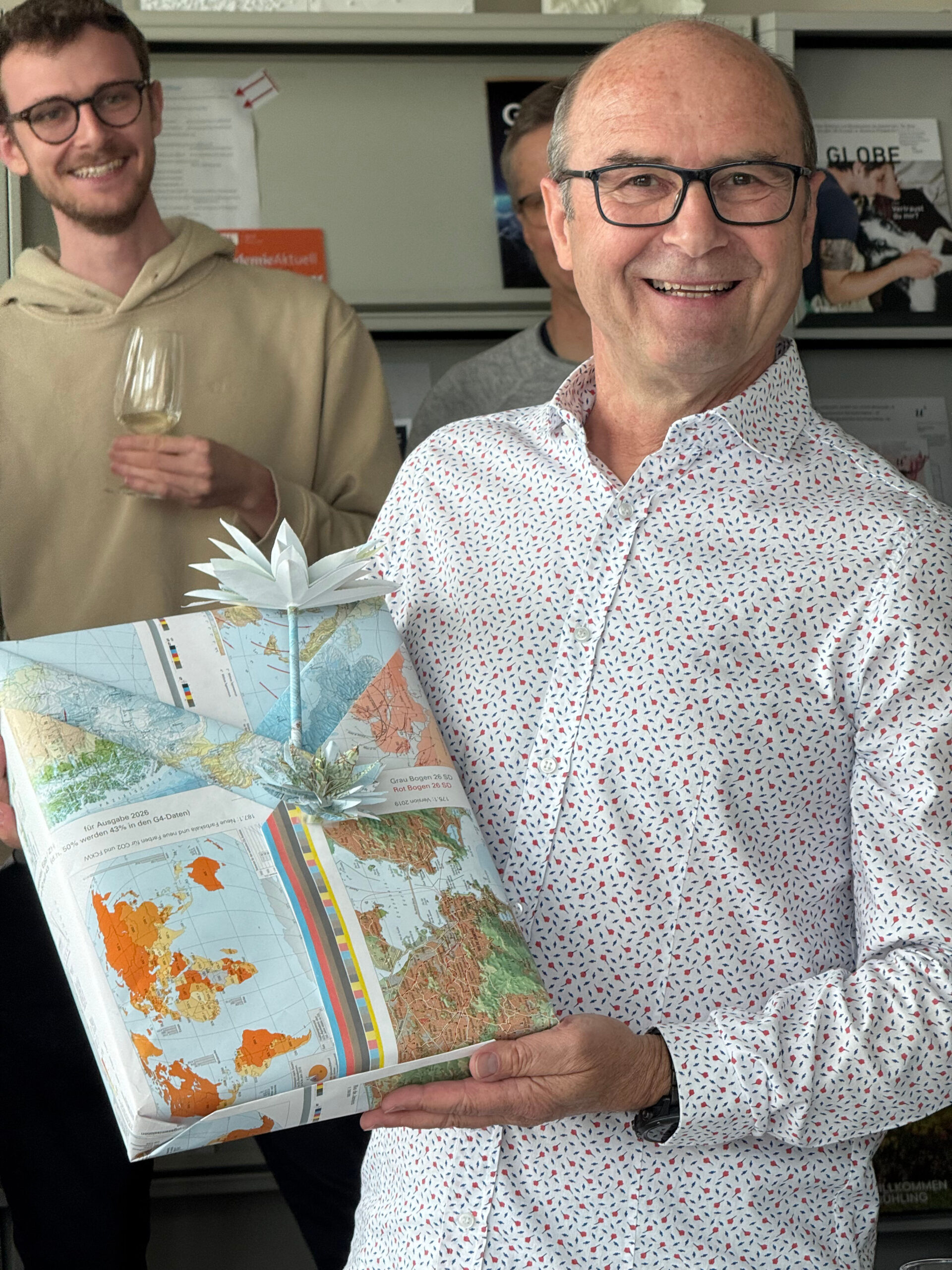 Homme recevant un cadeau d’adieu emballé dans du papier cartographique.